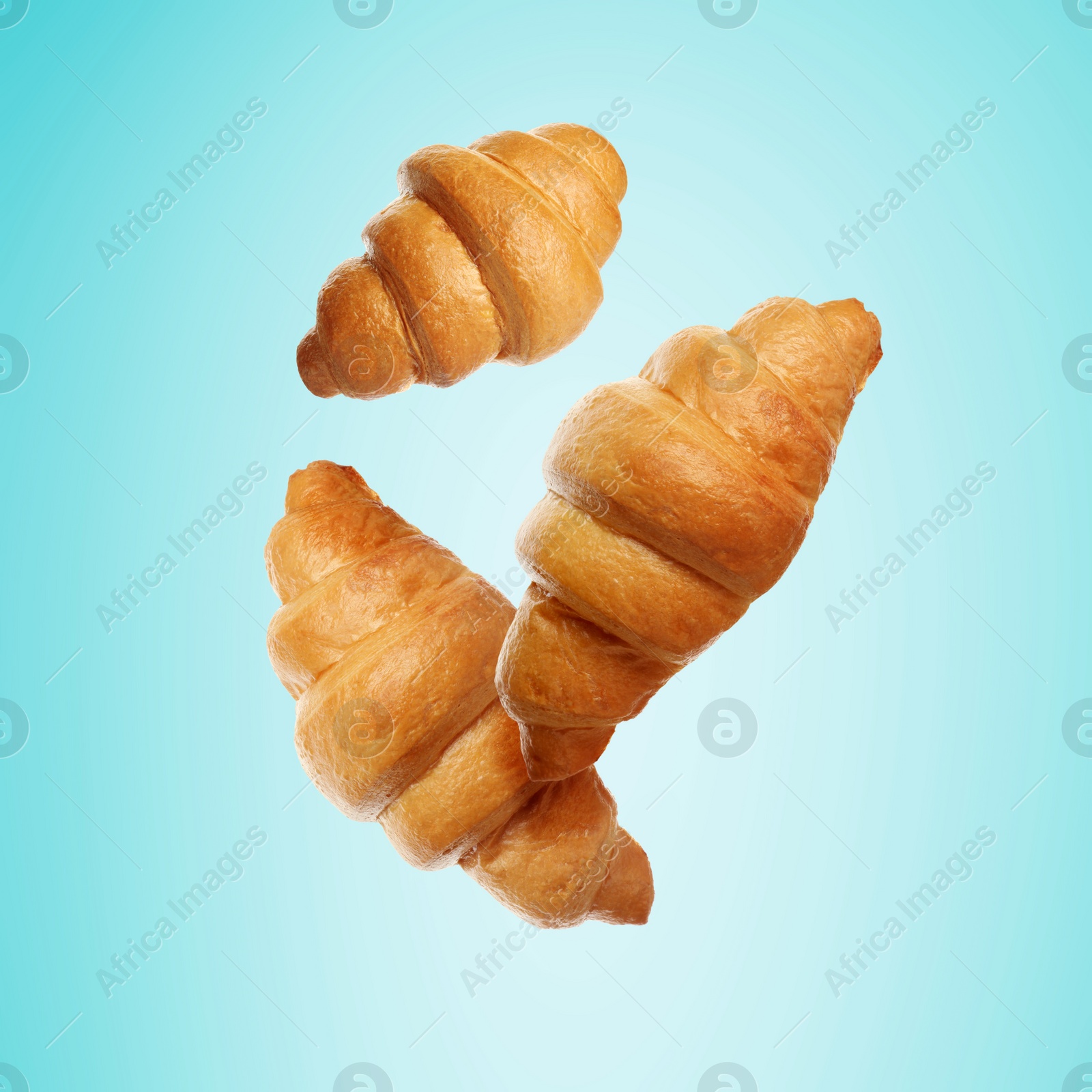 Image of Golden croissants falling on cyan gradient background