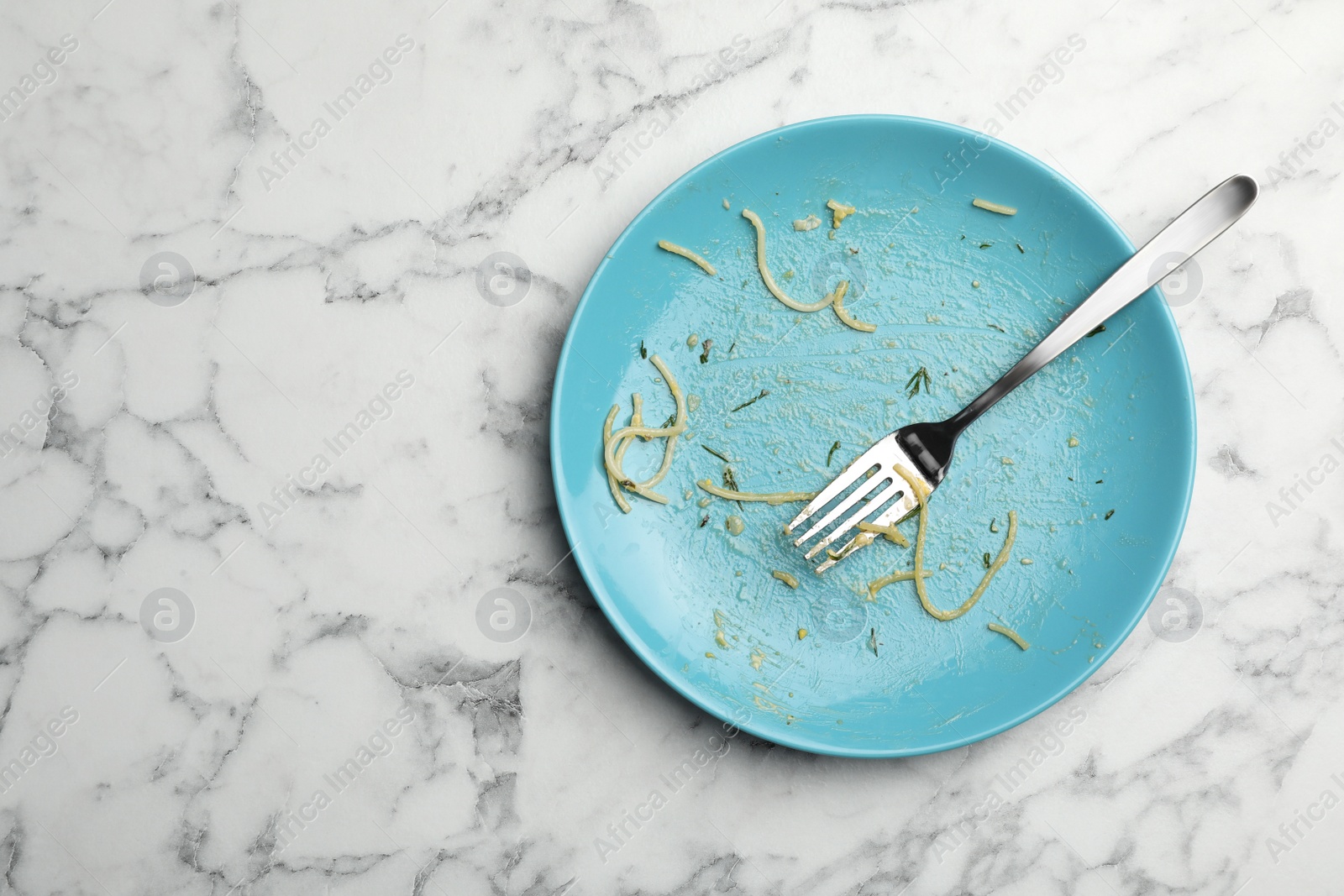 Photo of Dirty plate with food leftovers and fork on marble background, top view. Space for text