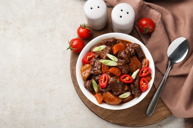 Photo of Delicious beef stew with carrots, chili peppers, green onions and potatoes served on white textured table, flat lay. Space for text