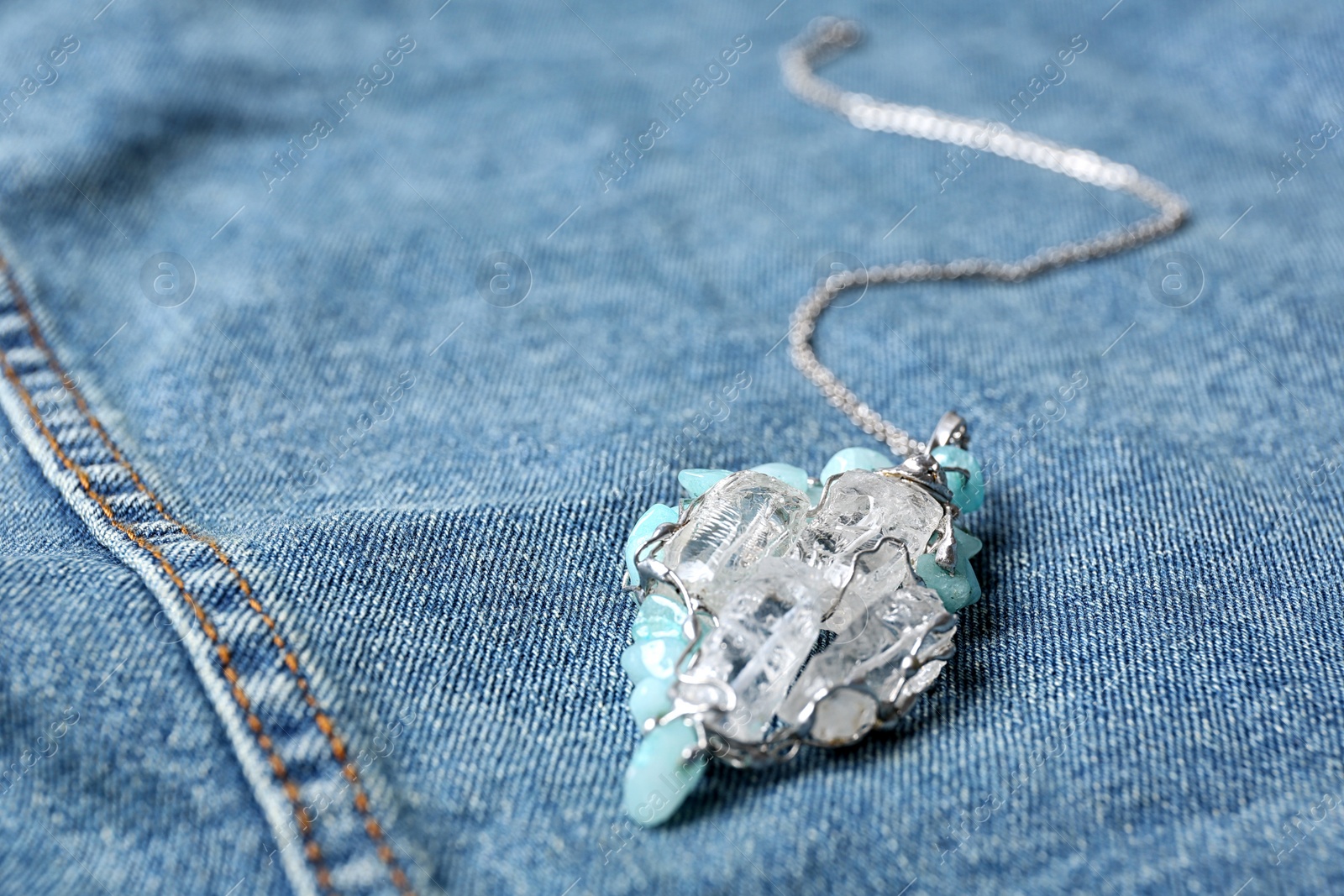Photo of Beautiful silver pendent with pure quartz gemstones on blue fabric. Space for text
