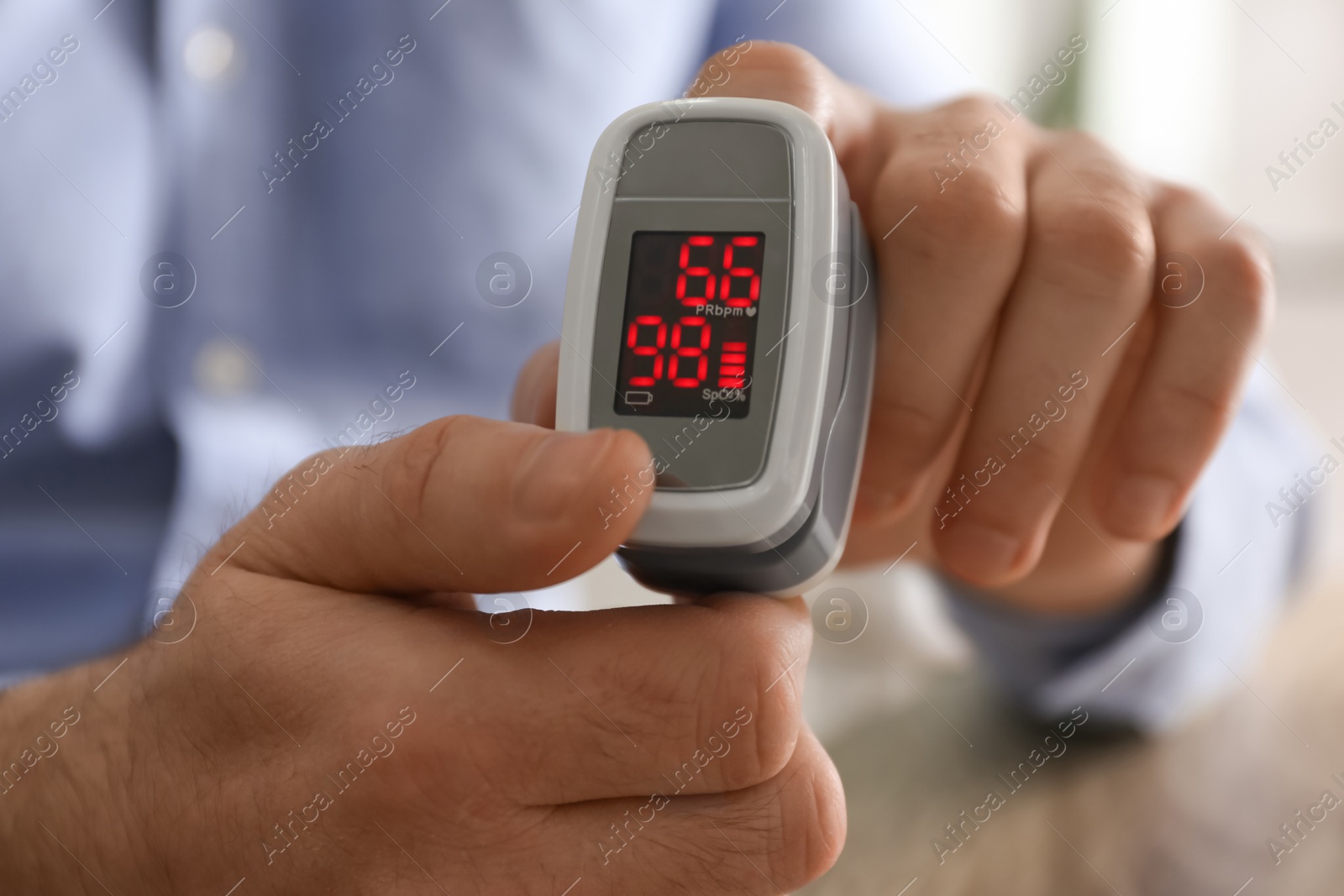 Photo of Man measuring oxygen level with modern fingertip pulse oximeter, closeup