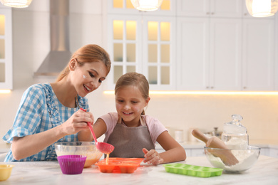 Photo of Mother and daughter making cupcakes together in kitchen