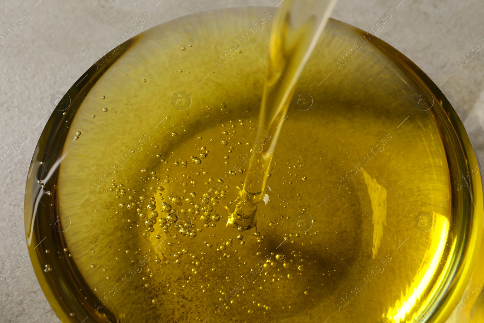 Photo of Pouring cooking oil into glass bowl, closeup