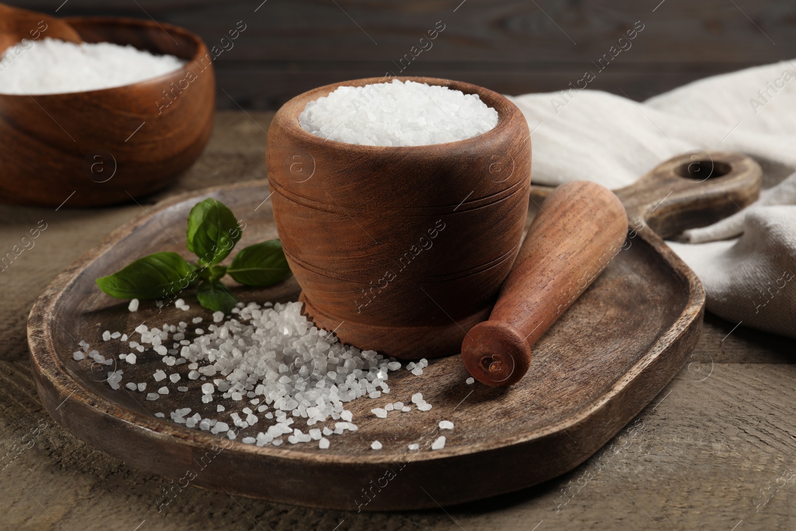 Photo of Pestle and mortar with natural sea salt on wooden table