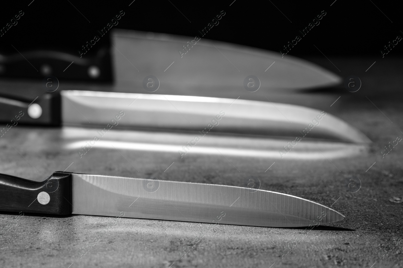 Photo of Sharp knives on table against dark background