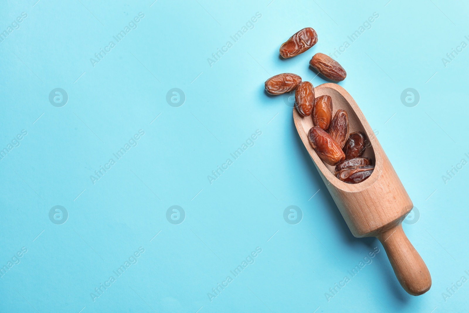 Photo of Scoop with sweet dried date fruits on color background, top view. Space for text