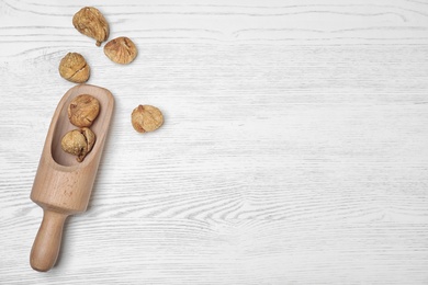 Scoop of dried figs on white wooden table, top view with space for text. Healthy fruit