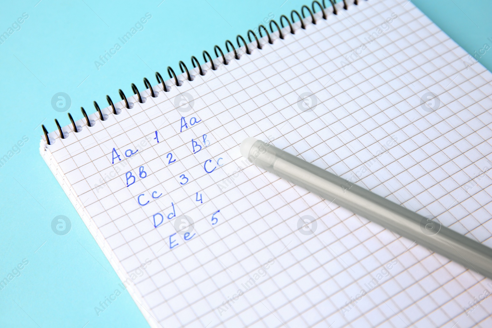 Photo of Letters and numbers written in notepad with erasable pen on light blue background, closeup