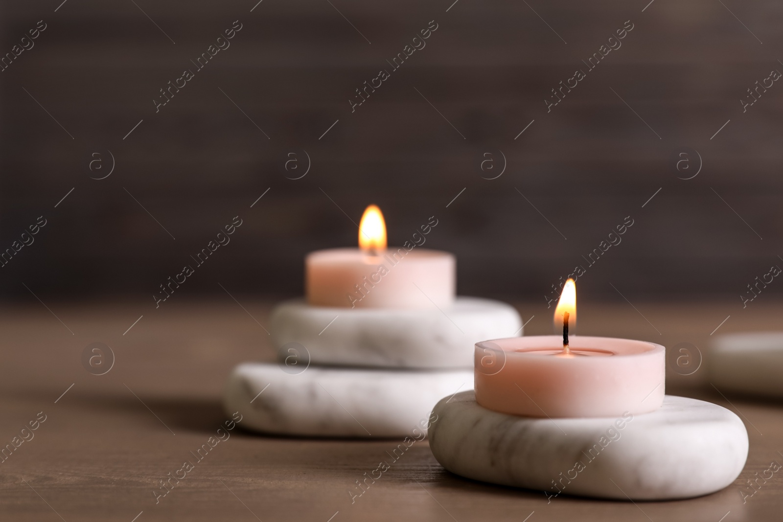 Photo of Spa stones and burning candles on wooden table. Space for text