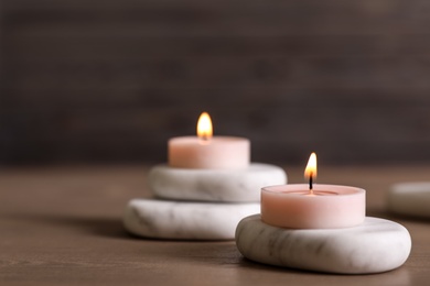 Spa stones and burning candles on wooden table. Space for text