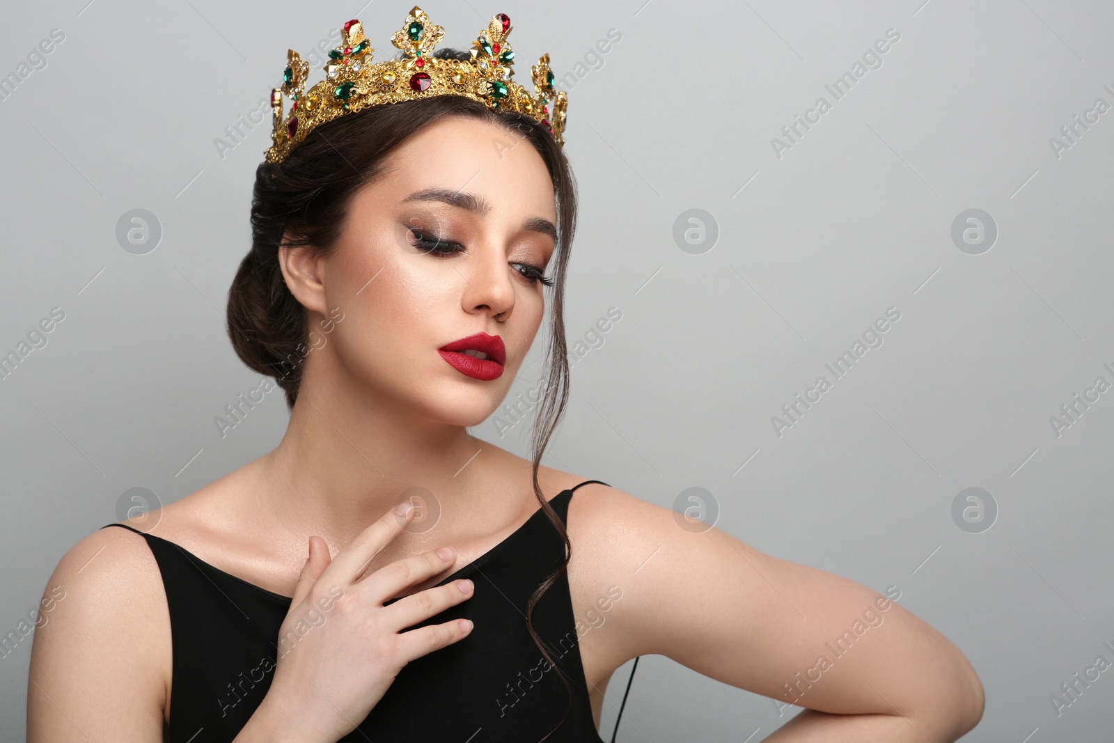 Photo of Beautiful young woman wearing luxurious crown on light grey background, space for text