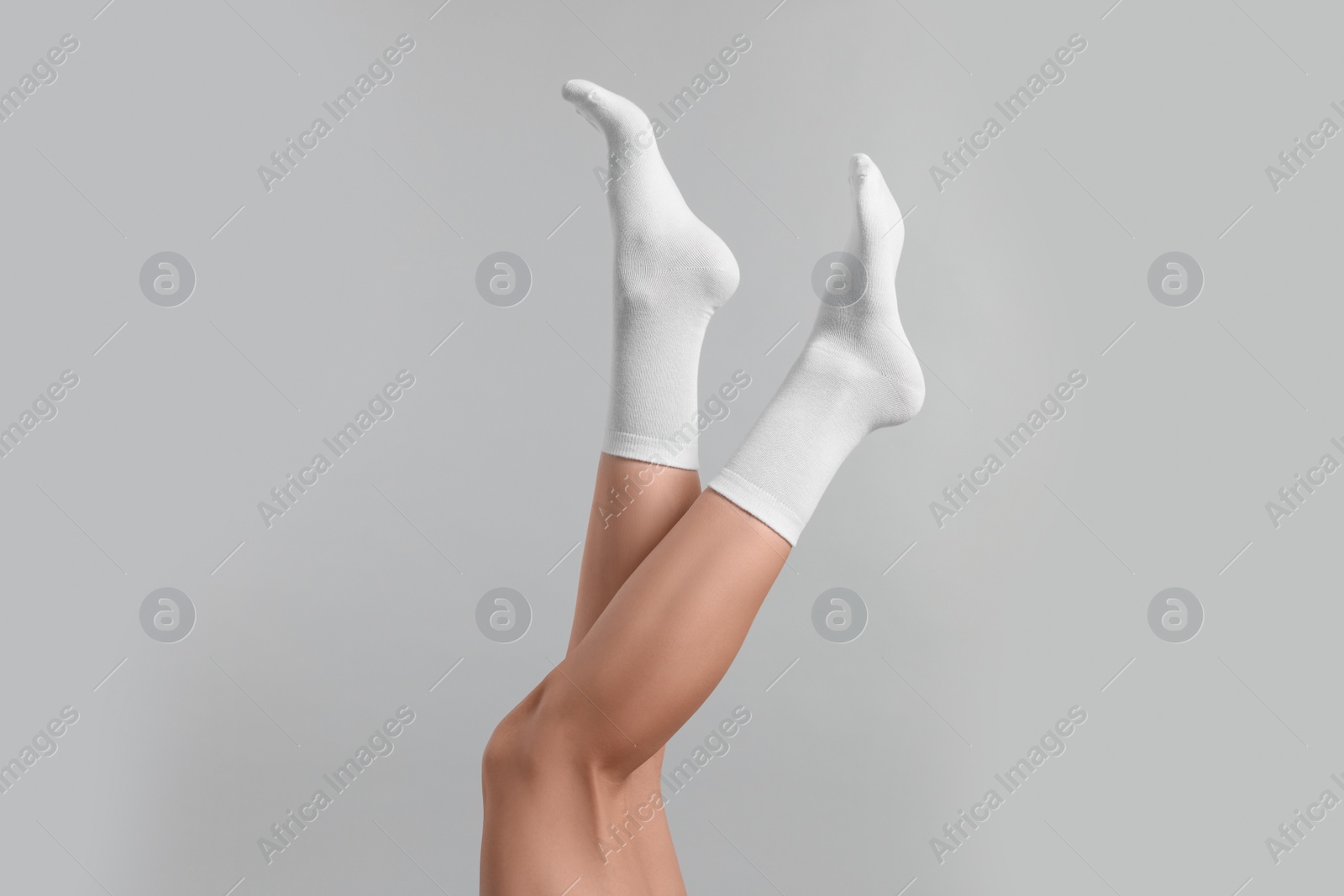 Photo of Woman in stylish white socks on light grey background, closeup