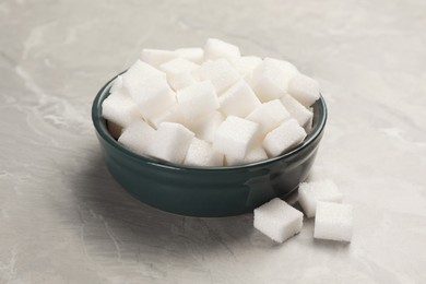 Photo of Bowl with sugar cubes on grey marble table, closeup