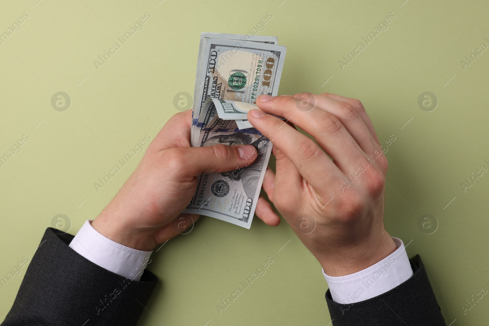 Photo of Money exchange. Man holding dollar banknotes on olive background, top view