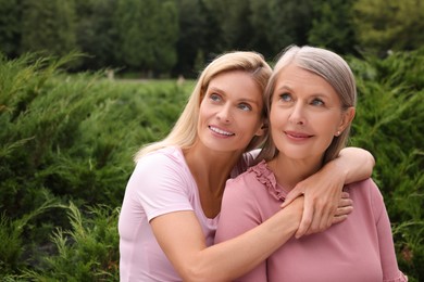 Happy mature mother and her daughter hugging outdoors