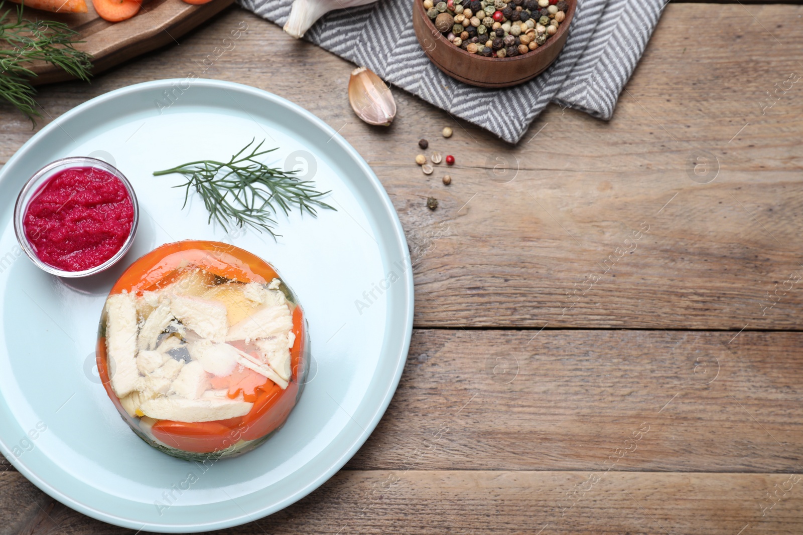 Photo of Delicious chicken aspic served on wooden table, flat lay. Space for text