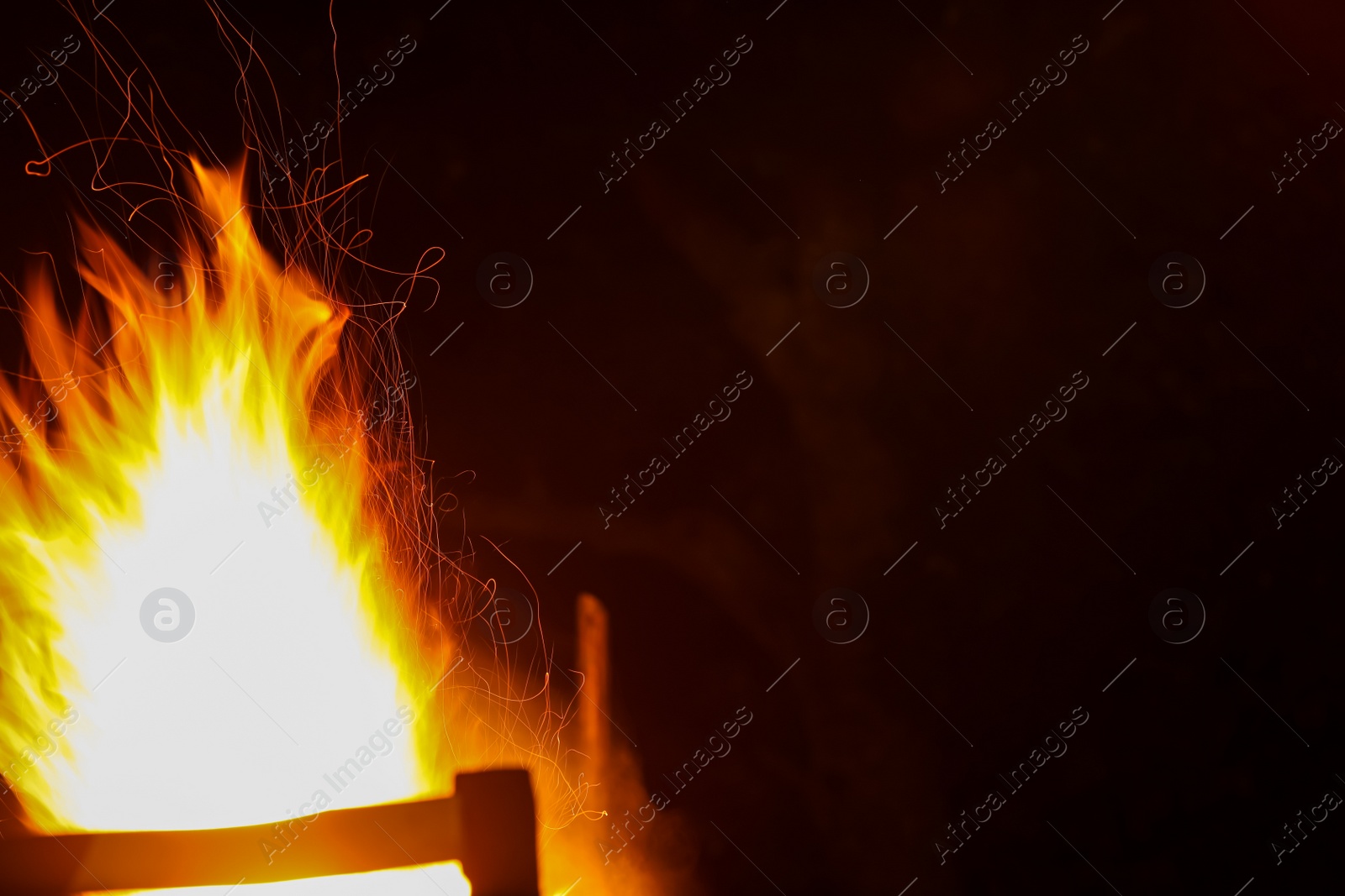 Photo of Bright flame outdoors at night. Space for text