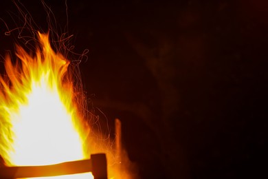 Photo of Bright flame outdoors at night. Space for text