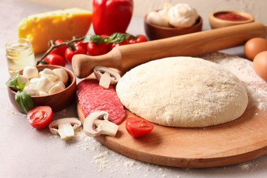Pizza dough, products and rolling pin on gray table, closeup