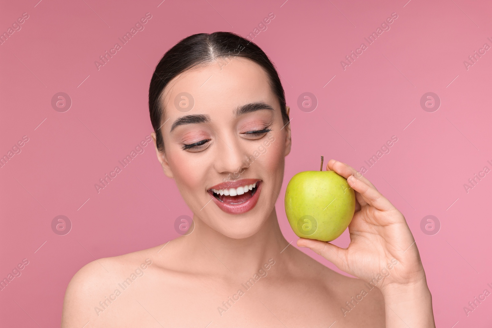 Photo of Beautiful young woman with apple on pink background