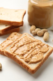 Photo of Delicious toasts with peanut butter and nuts on white table, closeup