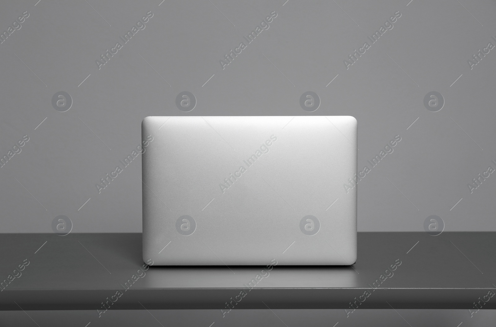 Photo of Modern laptop on table against gray background