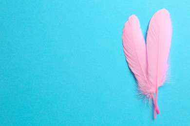 Photo of Beautiful pink feathers on light blue background, top view. Space for text
