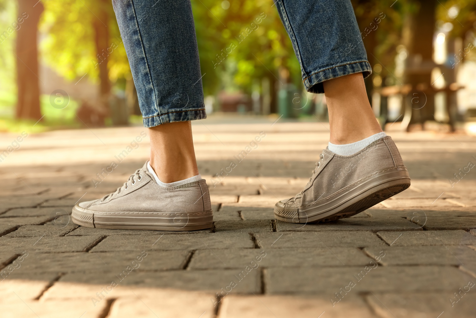 Photo of Woman in stylish sneakers walking on city street, closeup