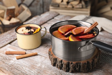 Photo of Delicious mulled wine and cinnamon on wooden table