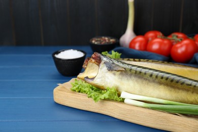 Delicious smoked mackerels, green onions and lettuce on blue wooden table, closeup. Space for text