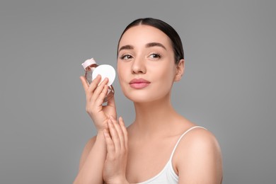 Photo of Beautiful woman with makeup remover and cotton pad on gray background