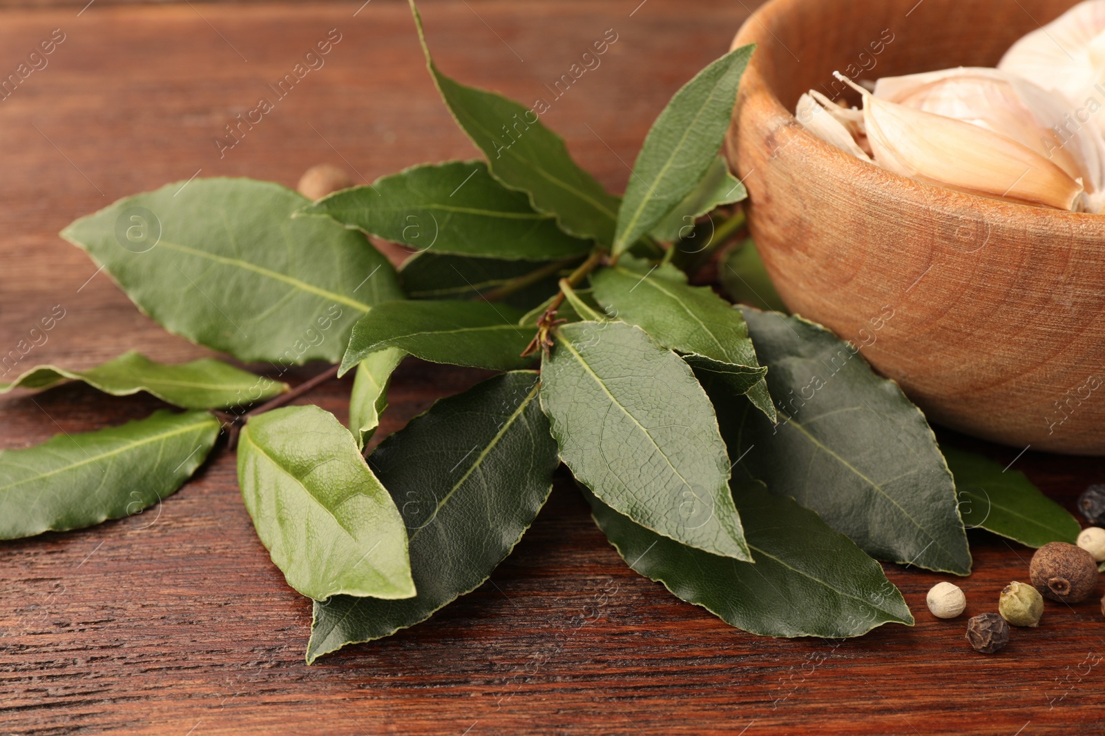 Photo of Aromatic fresh bay leaves and spices on wooden table, closeup