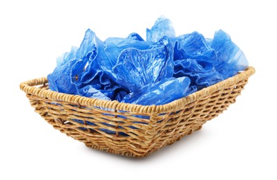 Blue medical shoe covers in wicker basket isolated on white