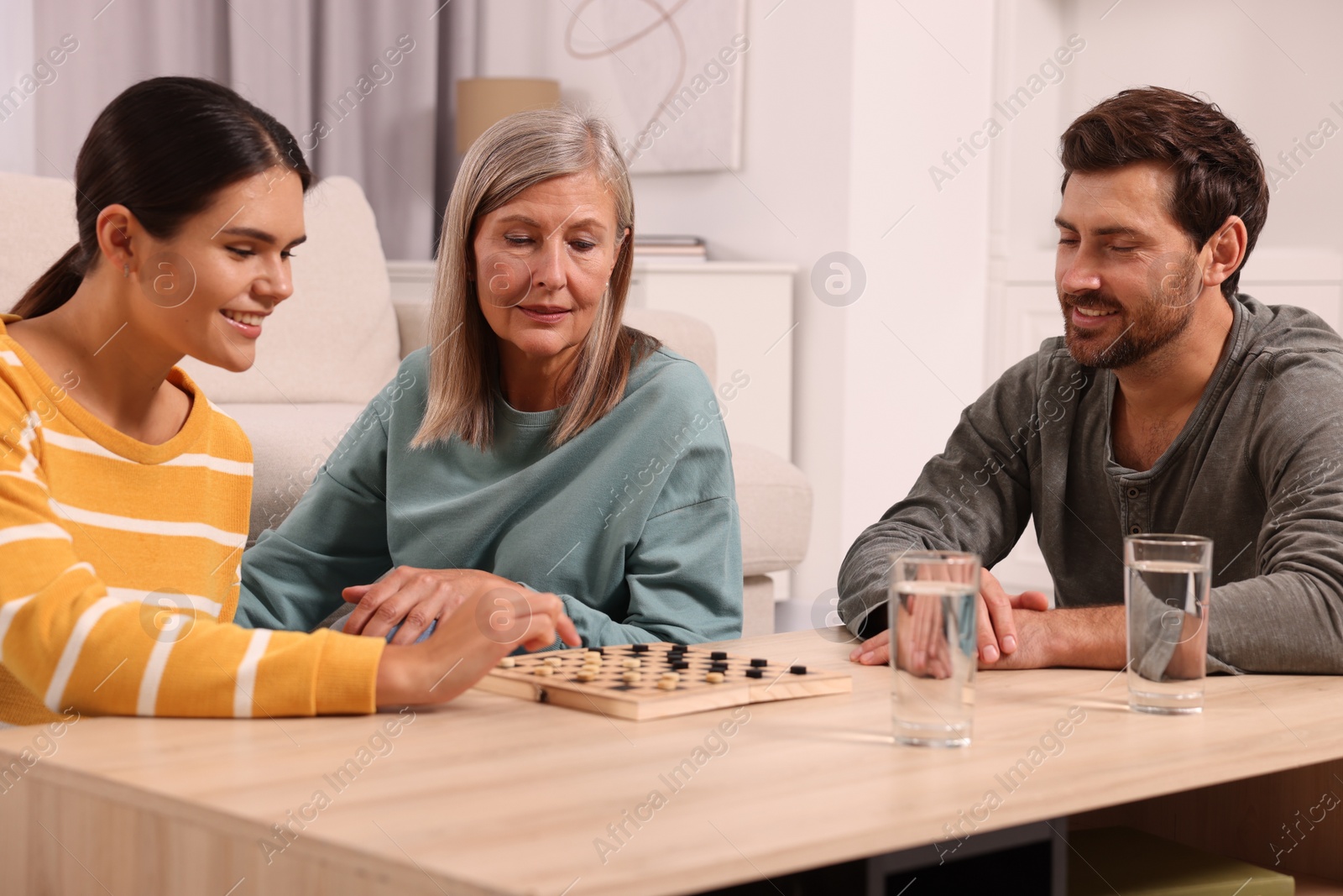 Photo of Family playing checkers at wooden table in room