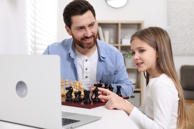 Photo of Father teaching his daughter to play chess following online lesson at home