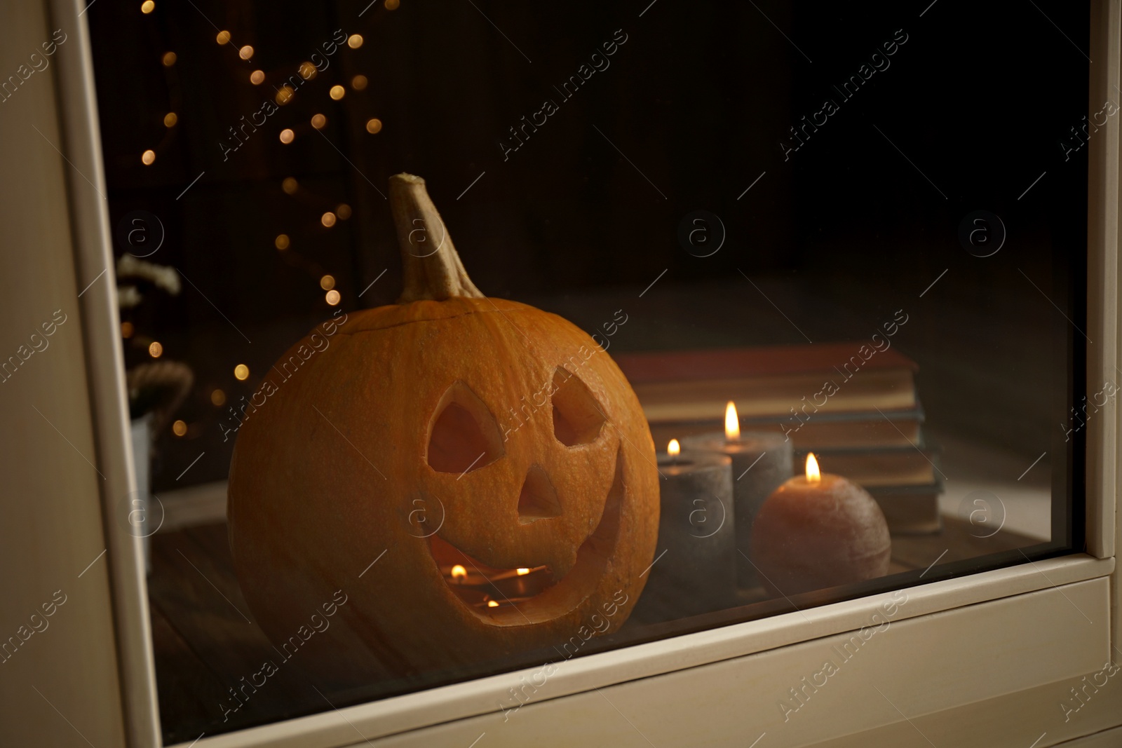 Photo of Composition with pumpkin head on windowsill, view through glass. Jack lantern - traditional Halloween decor