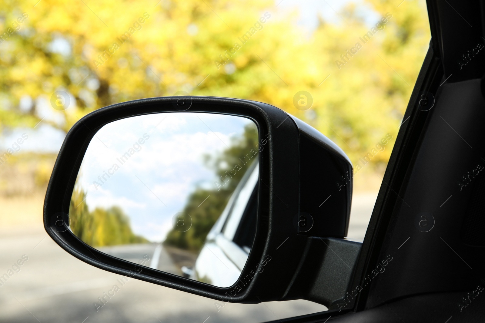 Photo of Closeup of car side rear view mirror on sunny day