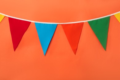 Bunting with colorful triangular flags on coral background. Festive decor