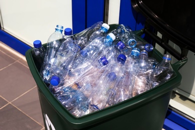 Photo of Many used plastic bottles in trash bin outdoors, closeup. Recycling problem