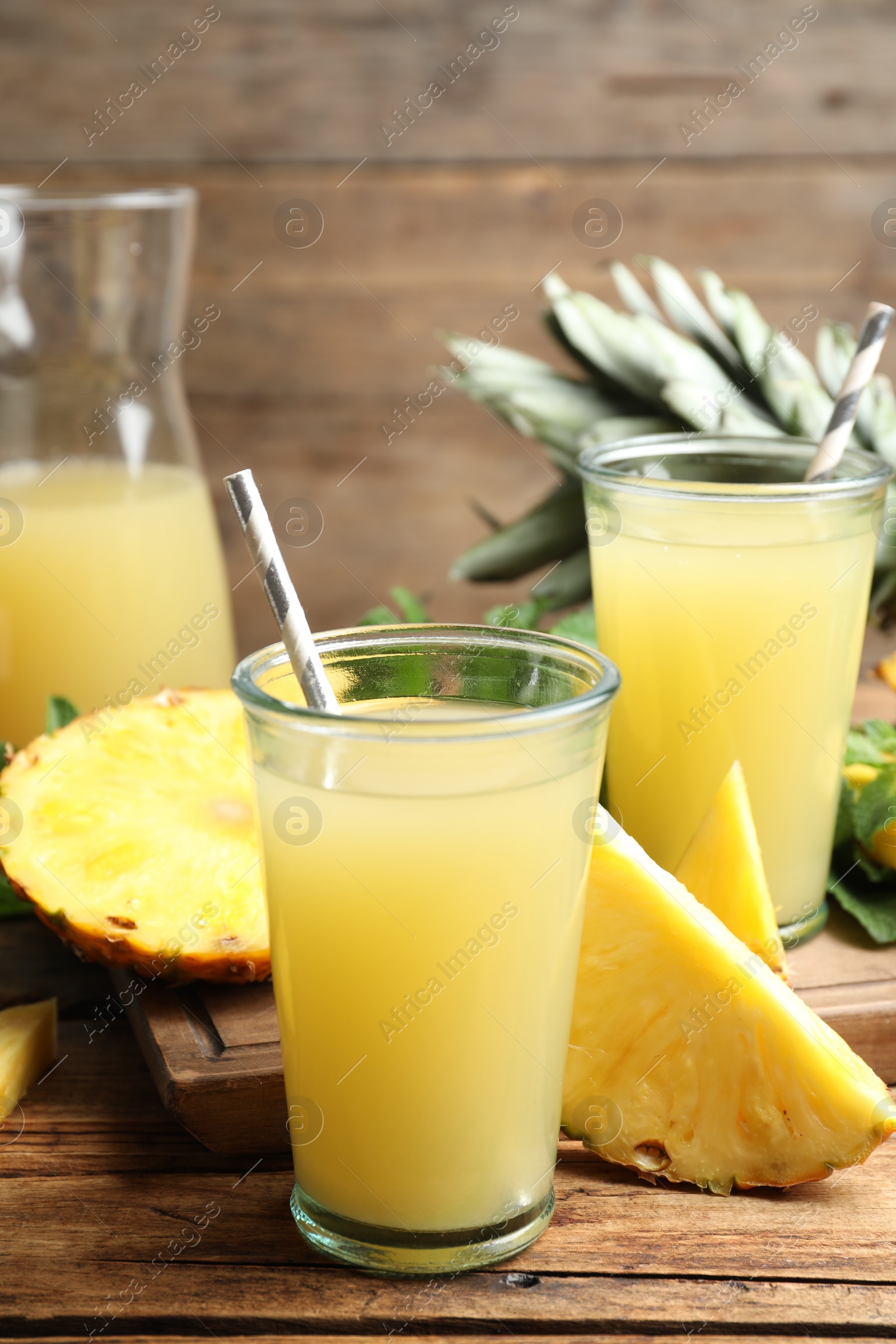 Photo of Delicious pineapple juice and fresh fruit on wooden table