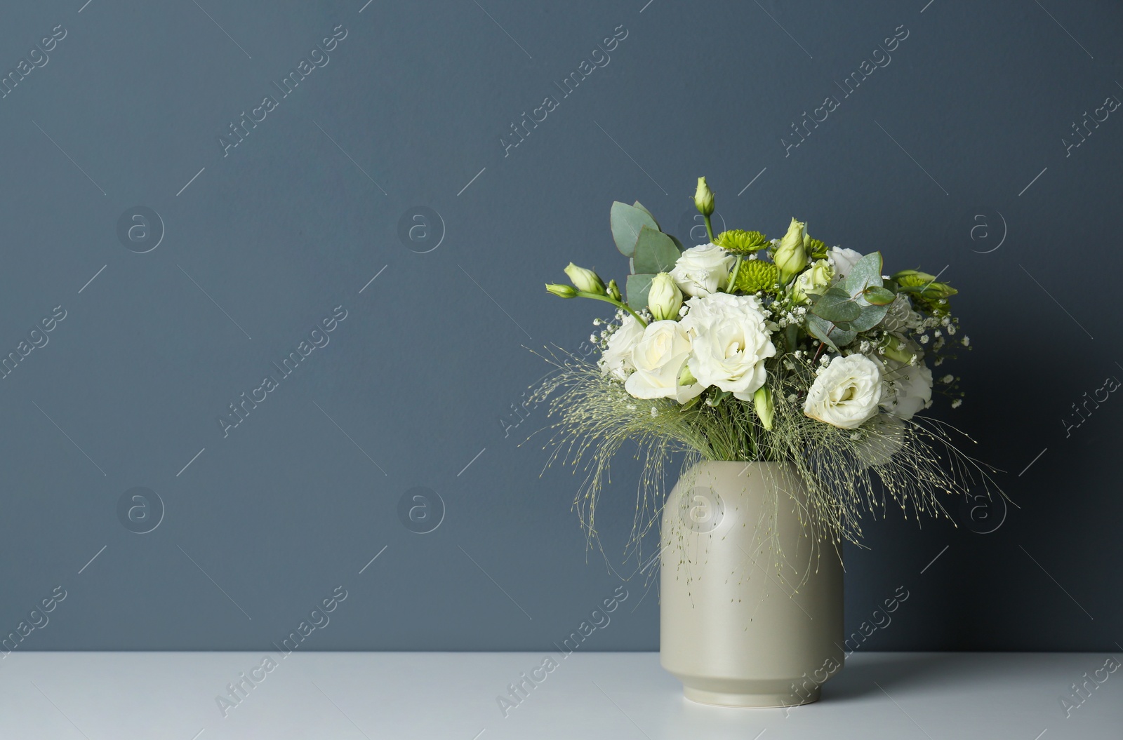 Photo of Bouquet with beautiful Eustoma flowers in vase on white table against grey background. Space for text