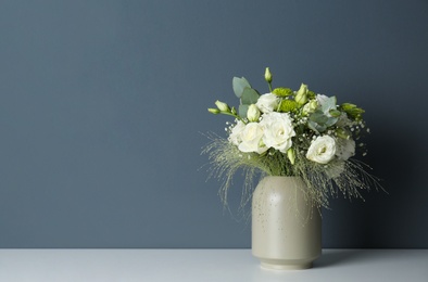 Bouquet with beautiful Eustoma flowers in vase on white table against grey background. Space for text