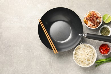 Photo of Flat lay composition with black wok, spices and products on grey textured table. Space for text