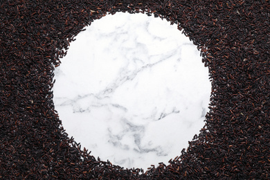 Photo of Frame made of brown rice on white marble table, top view. Space for text