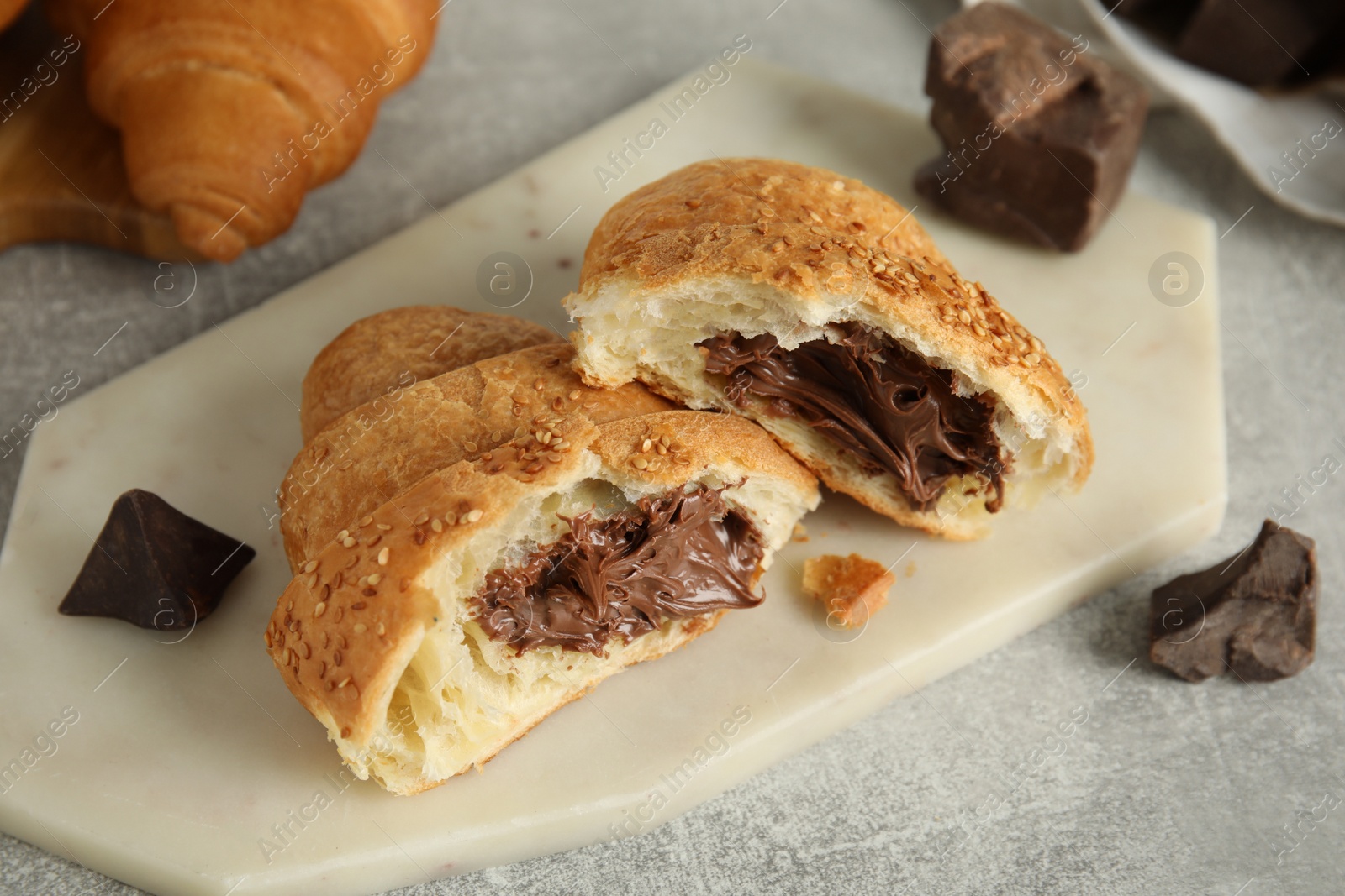 Photo of Tasty croissant with chocolate and sesame seeds on light grey table