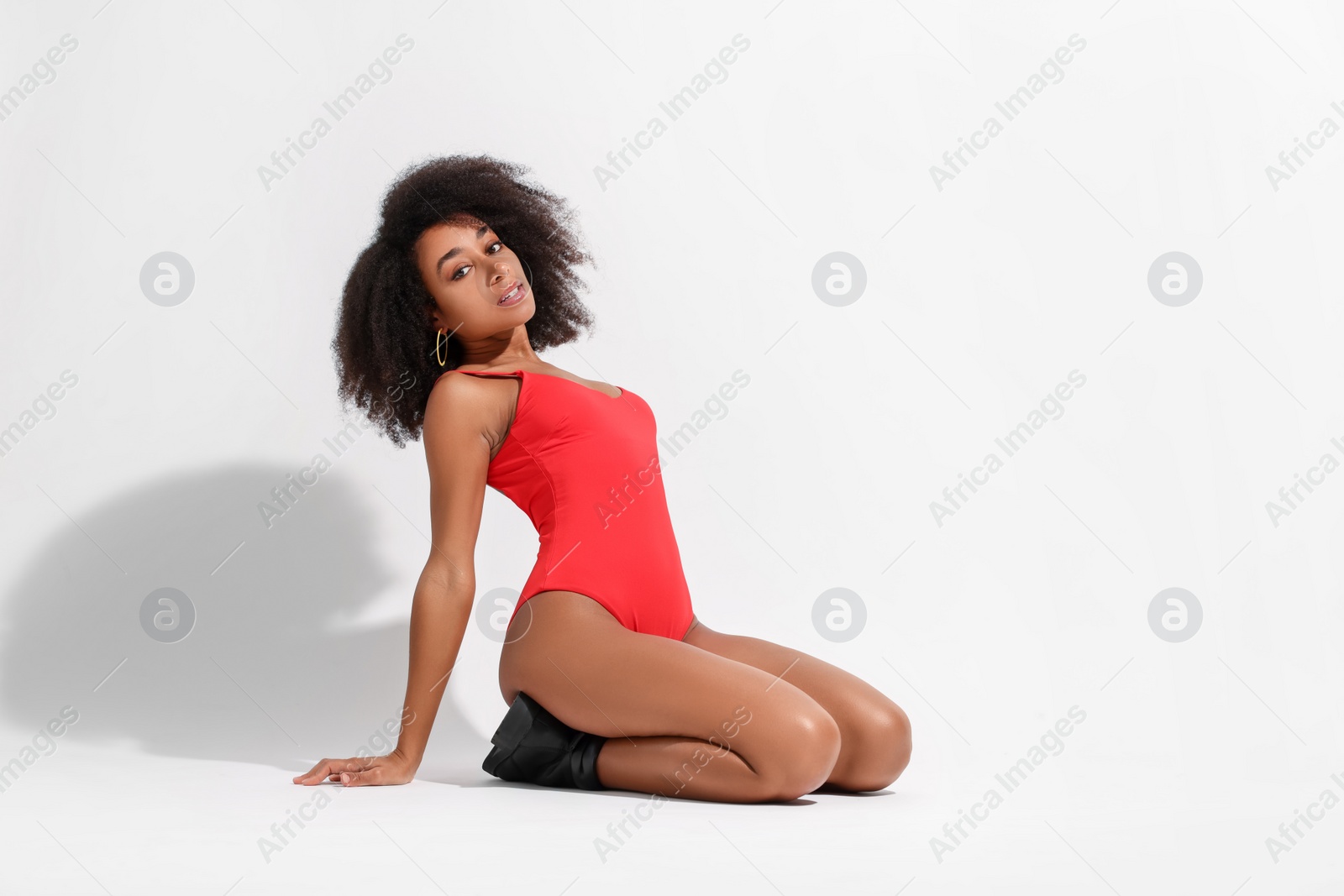 Photo of Beautiful woman in red one-piece summer swimsuit posing on white background, space for text