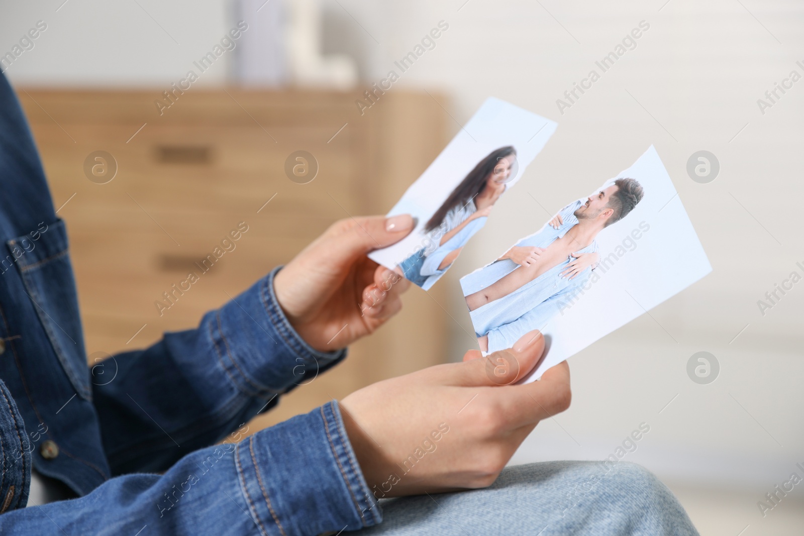 Photo of Woman holding torn photo at home, closeup. Divorce concept