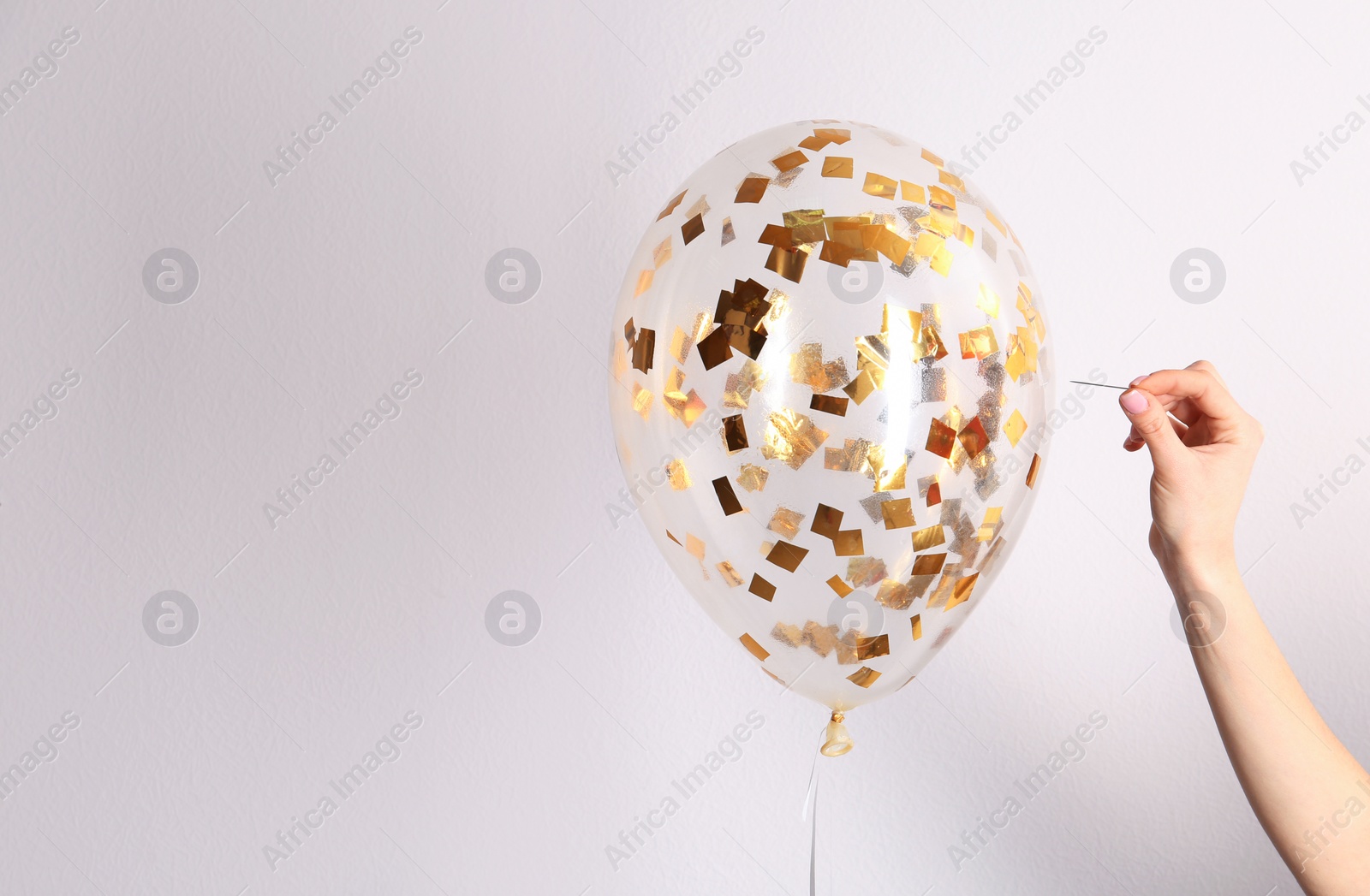 Photo of Woman piercing balloon with needle on white background, closeup