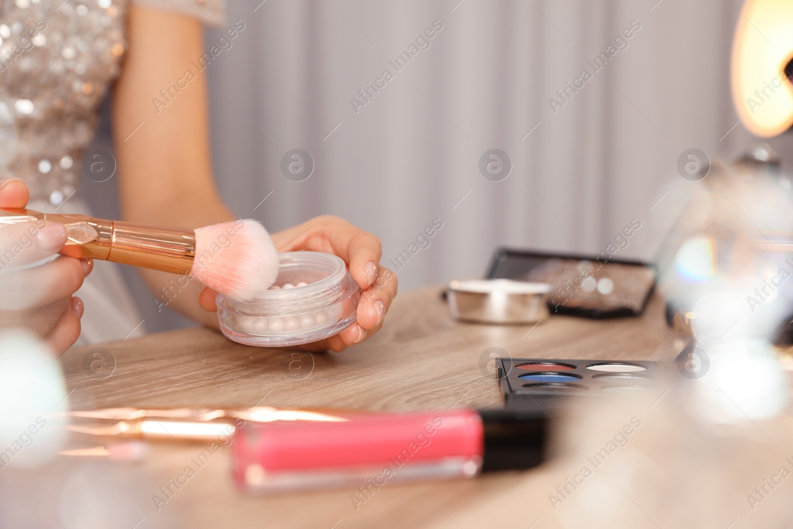 Photo of Woman applying makeup at dressing table, closeup