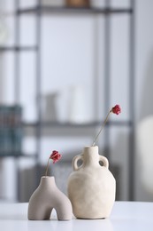 Photo of Vases with dried flowers on white table in room, space for text